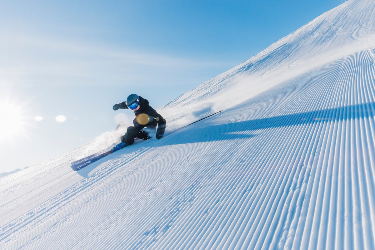 Skifahrerin carvt auf frisch präparierter Piste bei blauem Himmel, Salomon S/MAX