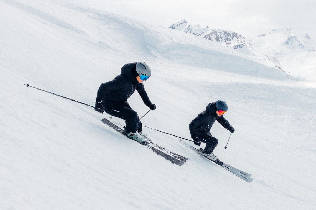 Zwei Skifahrer auf der Piste bei blauem Himmel