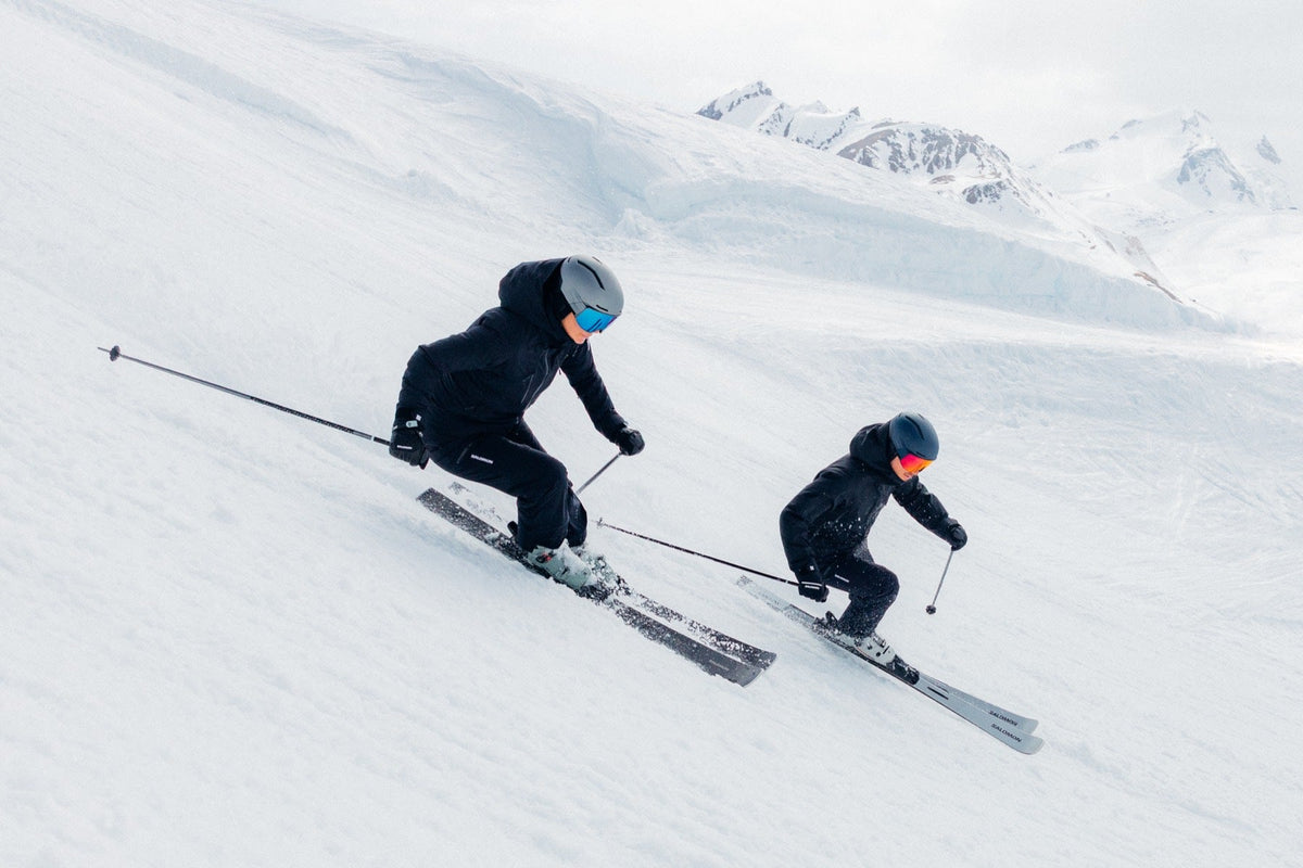 Zwei Skifahrer auf der Piste bei blauem Himmel