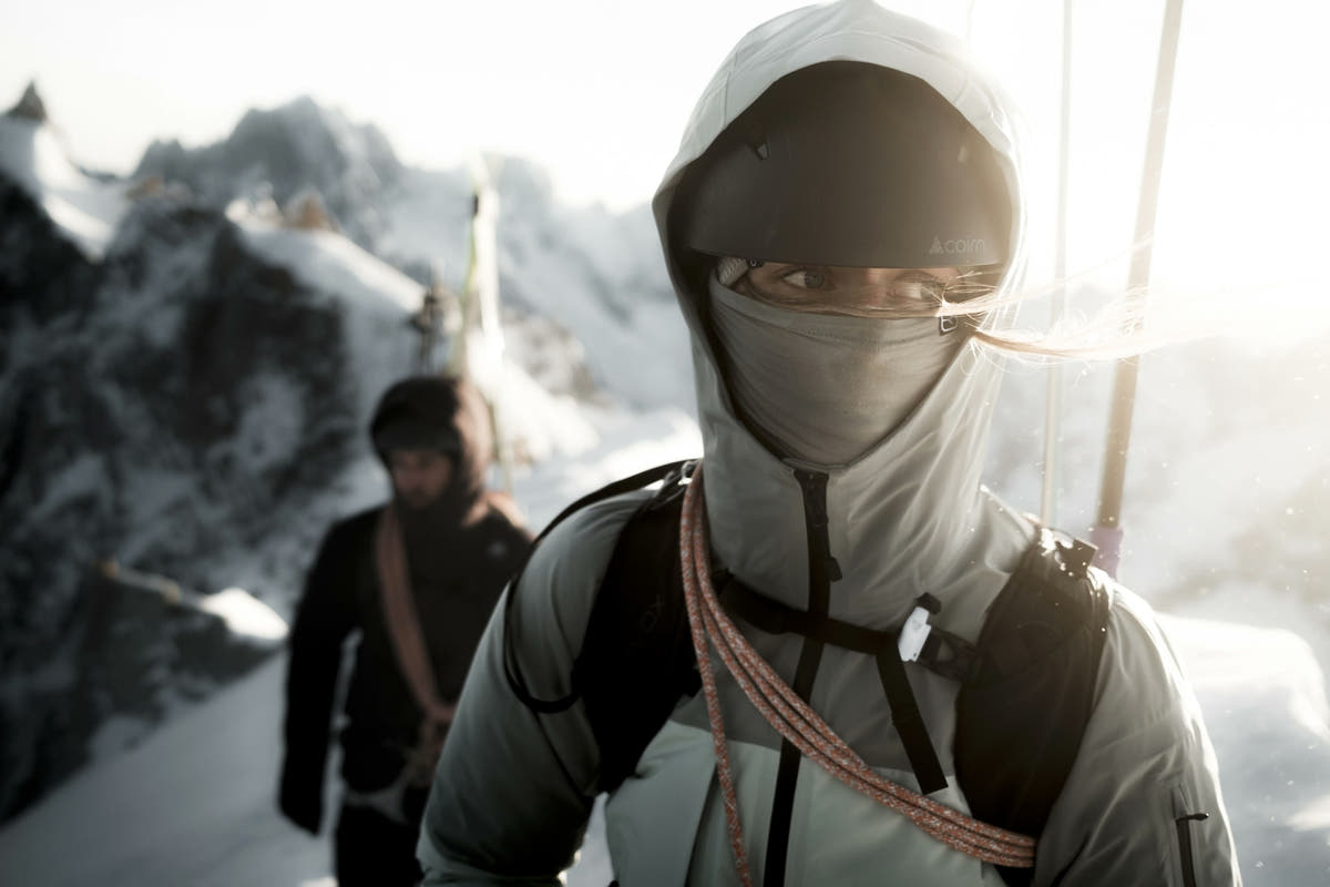Zwei Skitourengeher mit Seil und ORTOVOX Rucksäcken am Grat über Chamonix im Gegenlicht