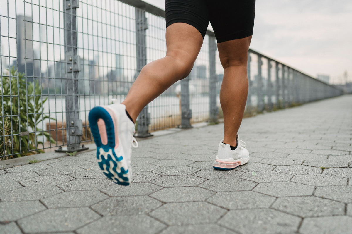 Laufschuhe und Beine beim Joggen auf einem gepflasterten Weg