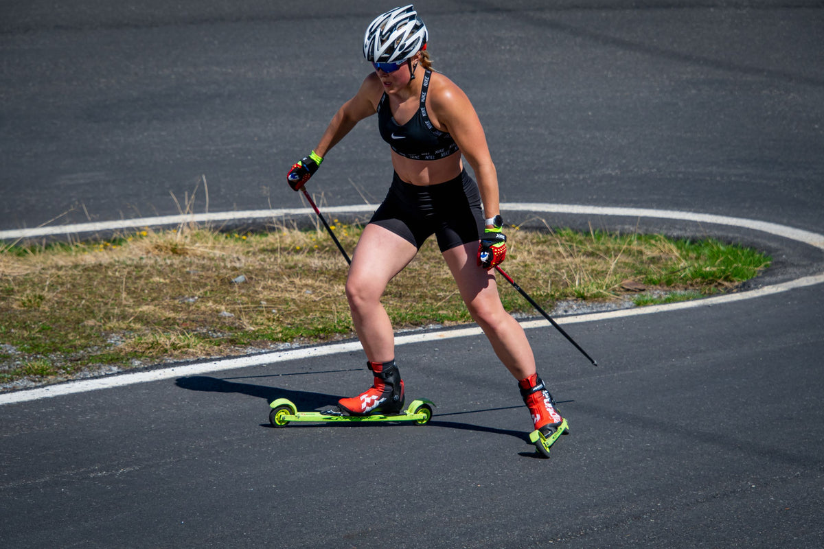 Skiroller, Langlaufschuhe und Stöcke beim Sommertraining auf einer Asphaltstrecke.