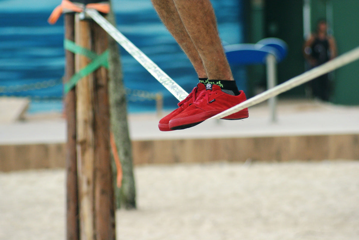 Nahaufnahme roter Schuhe beim Balancieren auf einer Slackline