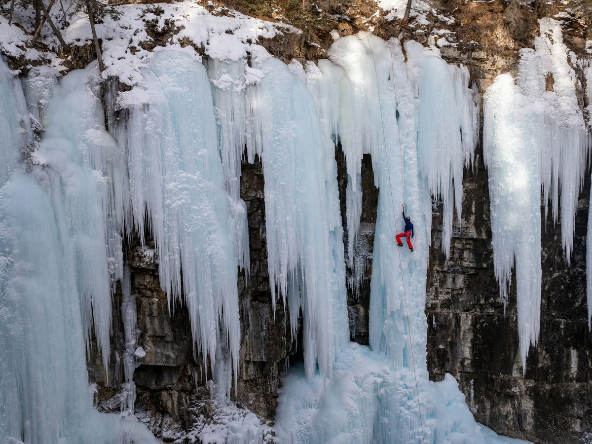 Eiskletterer mit Eisgeräten an einem gefrorenen Wasserfall bei Banff.