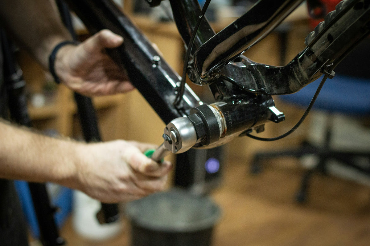 Mechaniker arbeitet mit einem Werkzeug am Tretlager eines Fahrrads