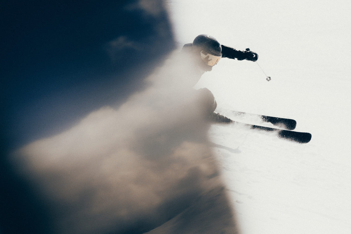 Volant Skifahrer zieht einen präzisen Schwung durch aufwirbelnden Schnee