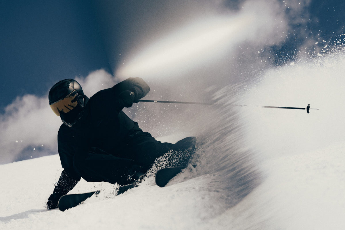 Volant Skifahrer carvt durch aufstiebenden Schnee
